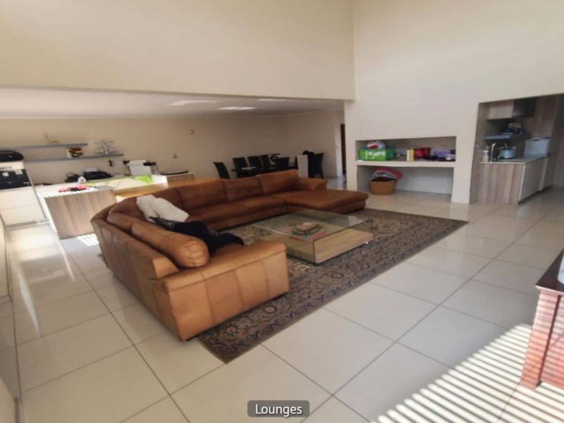 Spacious open-plan living area featuring high ceilings, tiled flooring, and an integrated kitchen space with built-in cabinetry and recessed shelving.