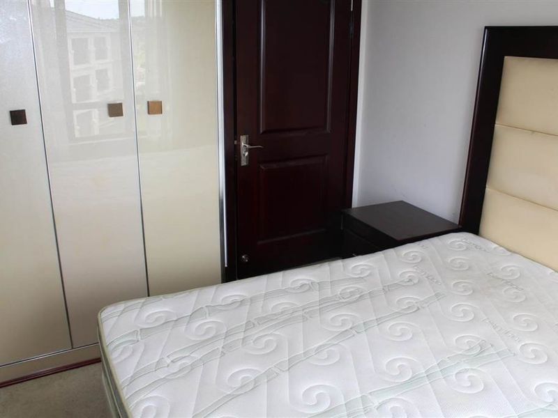 A bedroom featuring a built-in wardrobe with high-gloss finish and a solid wood door, providing functional storage and classic interior finishes.