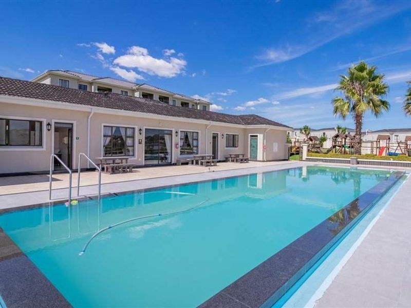 A well-maintained communal swimming pool area featuring a tiled deck, clear water, and direct access to the apartment building exterior.