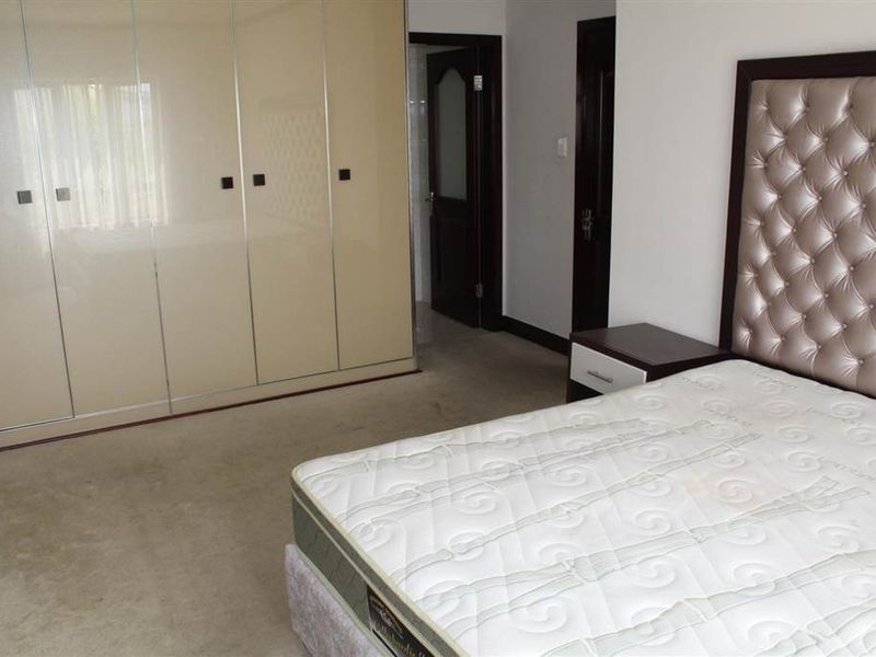 A bedroom featuring built-in wardrobes, carpeted flooring, and access to an adjoining room.