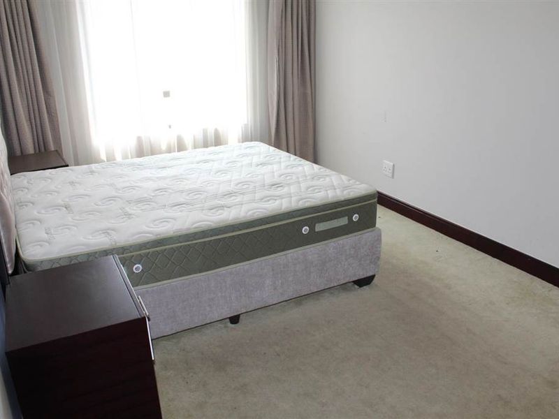 A bedroom featuring carpeted flooring and large windows with curtains, providing a neutral space ready for personalization.