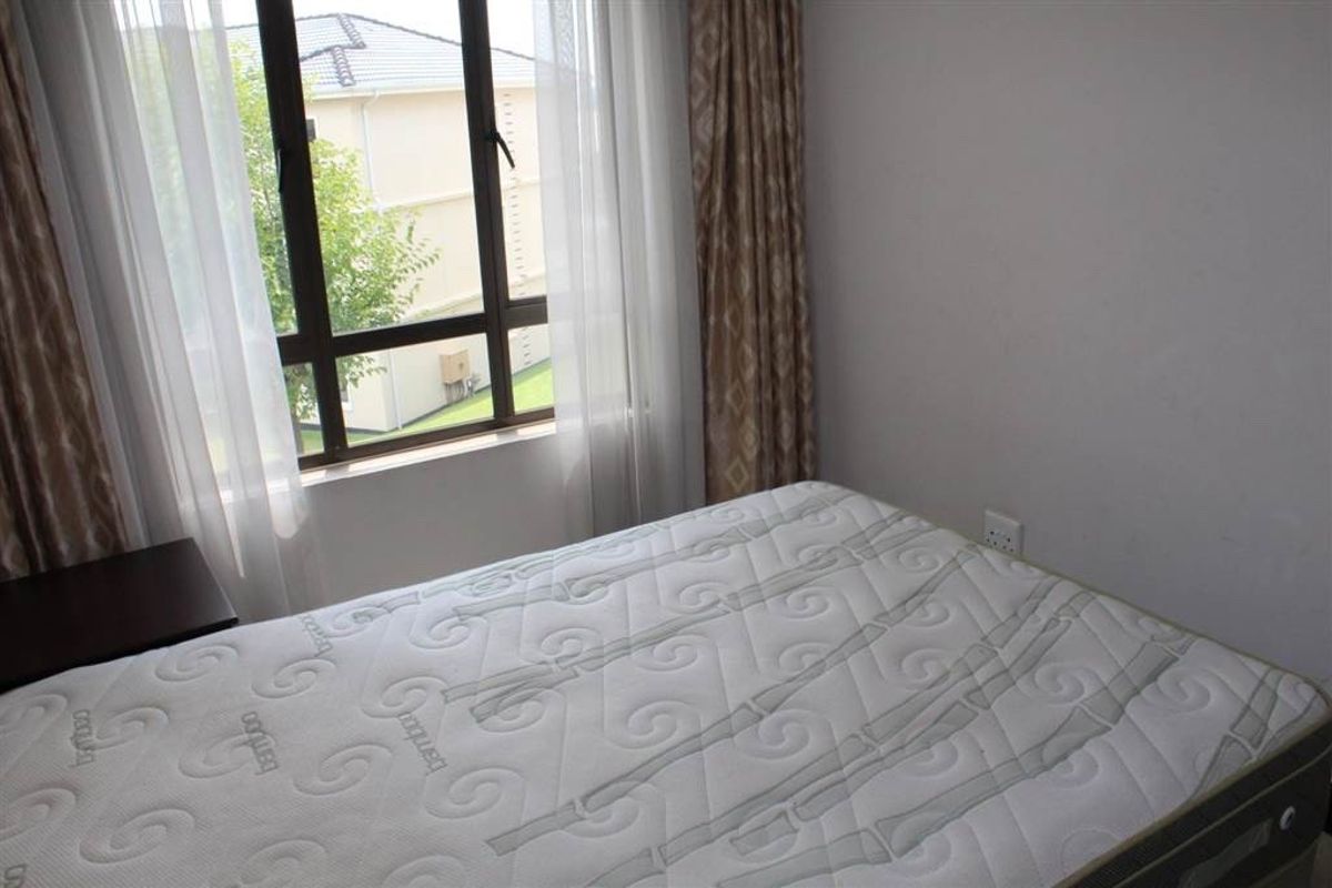 A bedroom featuring a large window with natural light and neutral wall finishes.