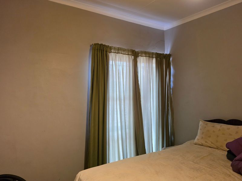 A bedroom featuring neutral wall finishes, cove cornicing, and a window fitted with a curtain rail.