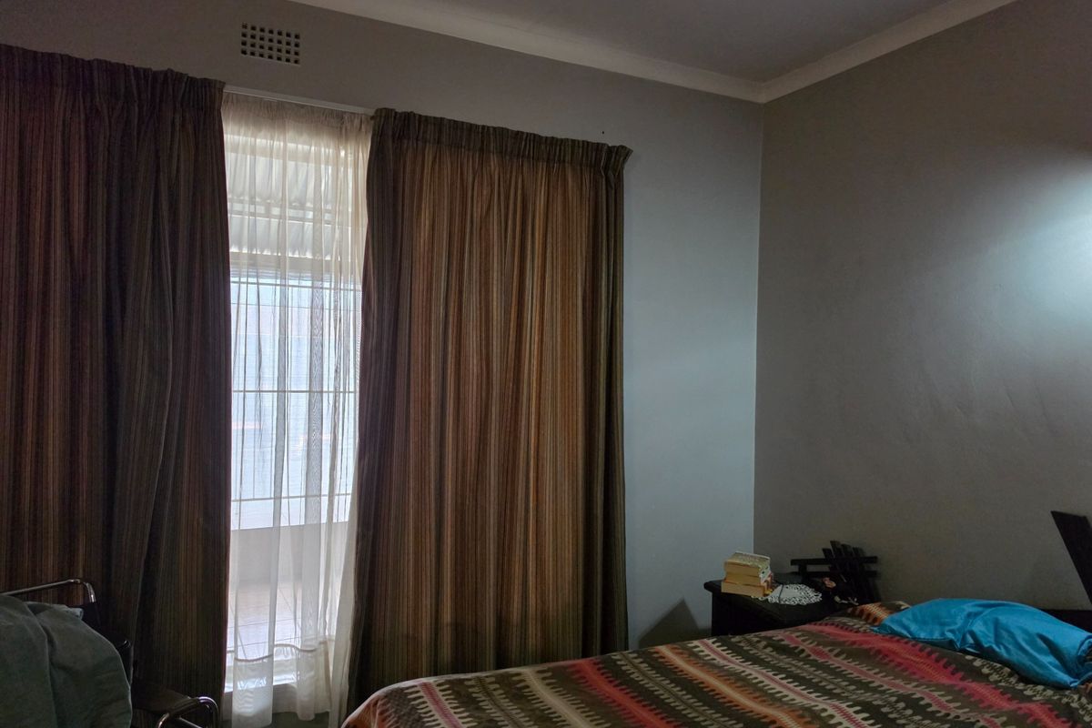 A bedroom featuring a sliding door with a security gate and neutral wall finishes, providing access to an outdoor area.