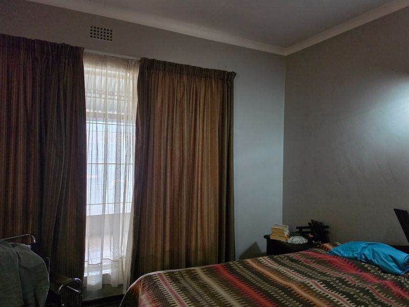 A bedroom featuring a sliding door with a security gate and neutral wall finishes, providing access to an outdoor area.