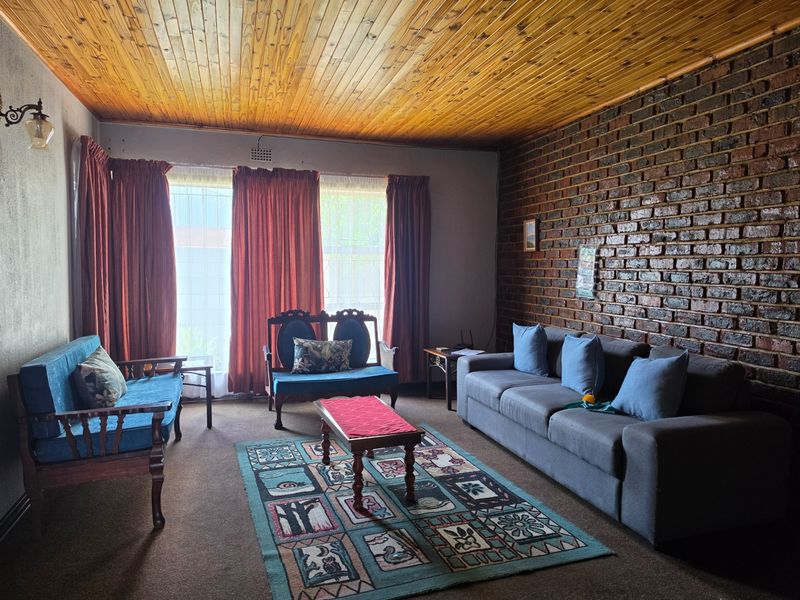 A living room featuring an exposed brick feature wall and a timber tongue and groove ceiling, offering a rustic aesthetic with potential for modernization.