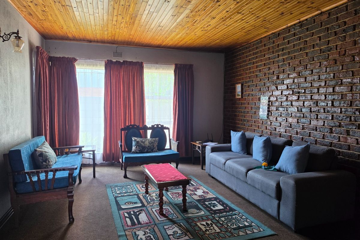 A living room featuring an exposed brick feature wall and a timber tongue and groove ceiling, offering a rustic aesthetic with potential for modernization.