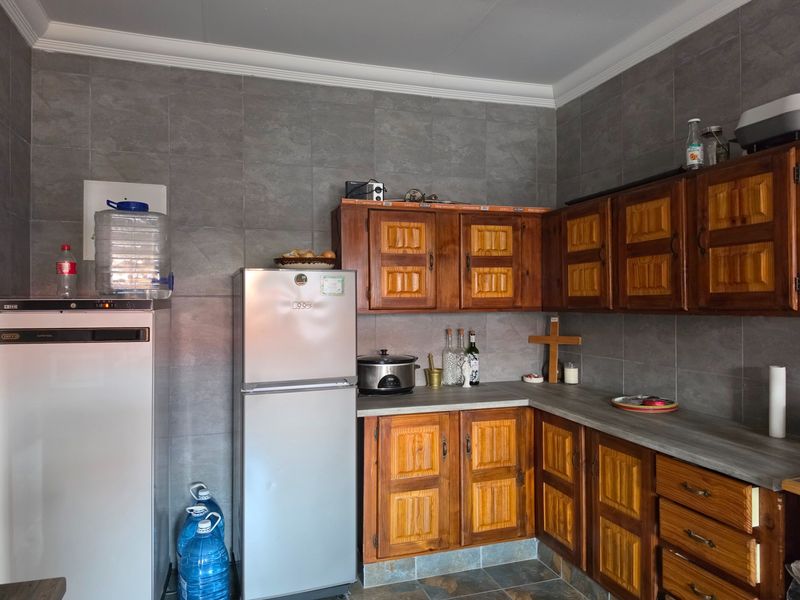 A functional kitchen featuring traditional wooden cabinetry, grey tiled wall splashbacks, and laminate countertops, offering a classic aesthetic with potential for modern updates.