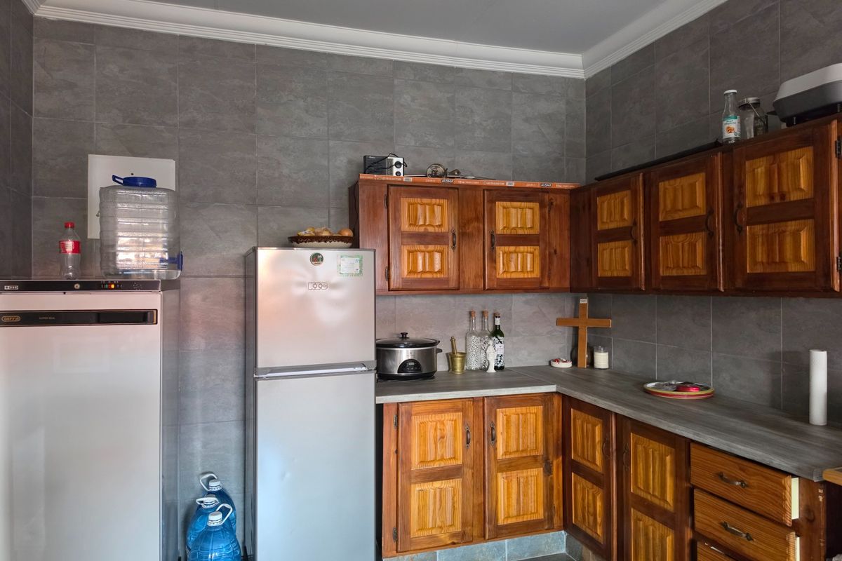 A functional kitchen featuring traditional wooden cabinetry, grey tiled wall splashbacks, and laminate countertops, offering a classic aesthetic with potential for modern updates.