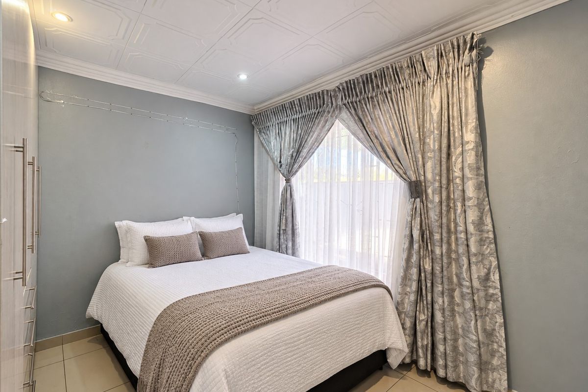 A well-maintained bedroom featuring built-in cupboards, tiled flooring, and decorative ceiling tiles with recessed lighting.