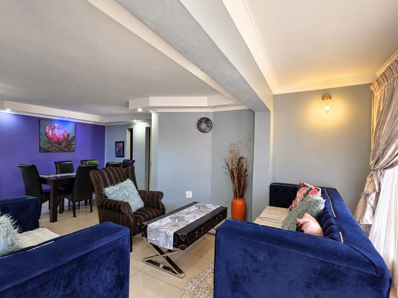 Spacious open-plan living and dining area featuring tiled flooring, recessed ceiling lighting, and decorative wall finishes.
