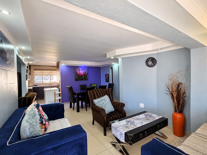 Spacious open-plan living and dining area featuring tiled floors, recessed lighting, and a connected kitchen space with built-in cabinetry.