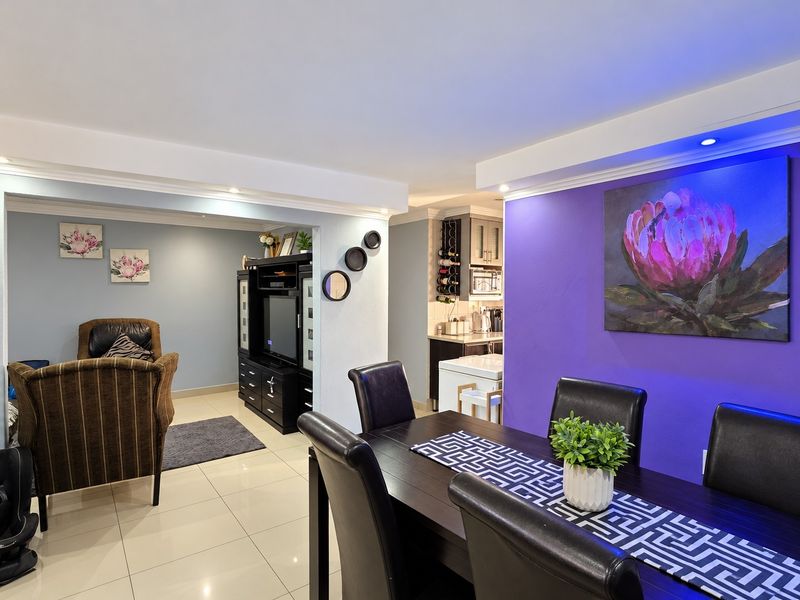Open-plan living and dining area featuring tiled floors, recessed lighting, and a connected kitchen space with built-in cabinetry.