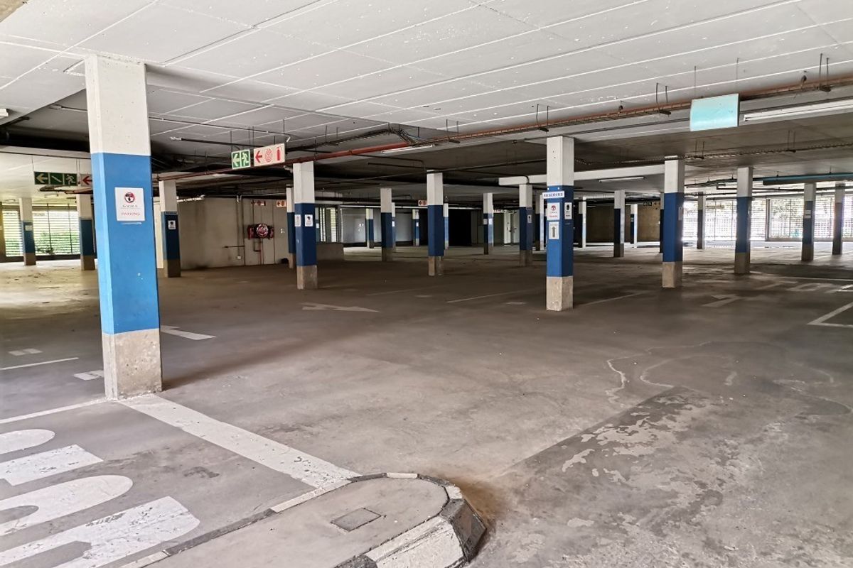 Spacious commercial underground parking garage featuring concrete flooring, structural support columns, and clear directional signage.