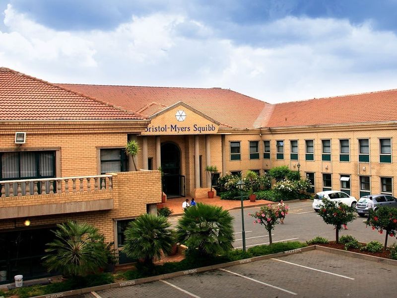 Front elevation of a commercial office building featuring brick construction, a tiled roof, and a dedicated visitor parking area.