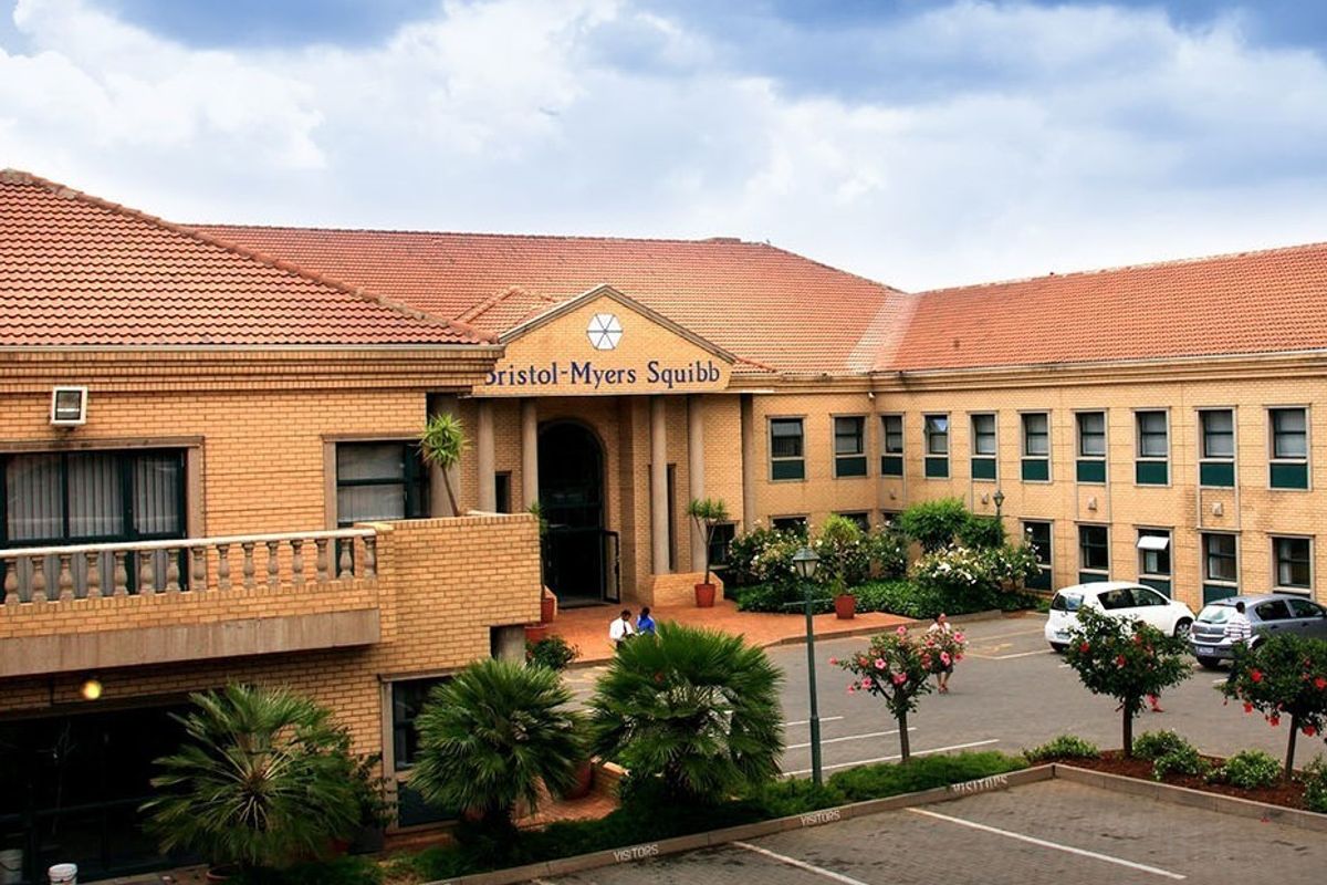 Front elevation of a commercial office building featuring brick construction, a tiled roof, and a dedicated visitor parking area.