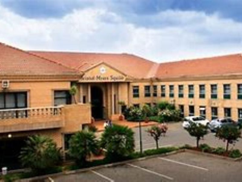 Front elevation of a commercial office building featuring brick construction, a tiled roof, and an integrated paved parking area.