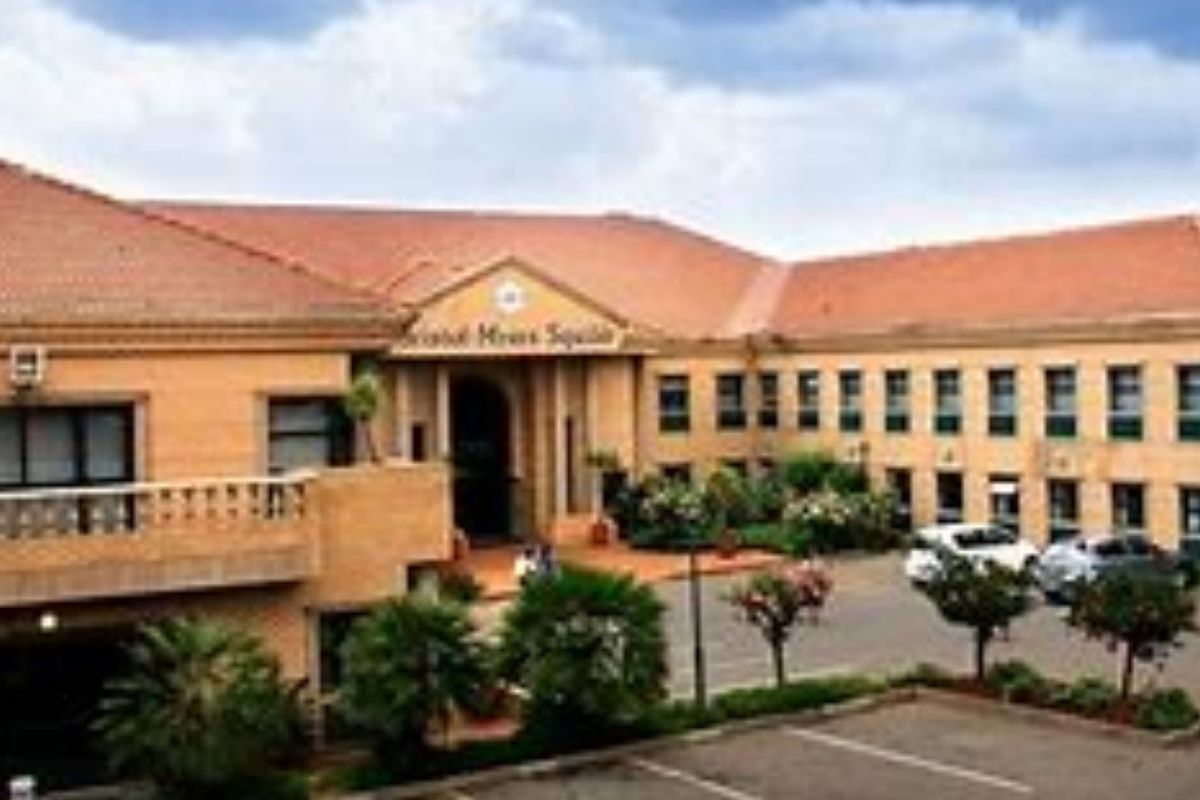 Front elevation of a commercial office building featuring brick construction, a tiled roof, and an integrated paved parking area.