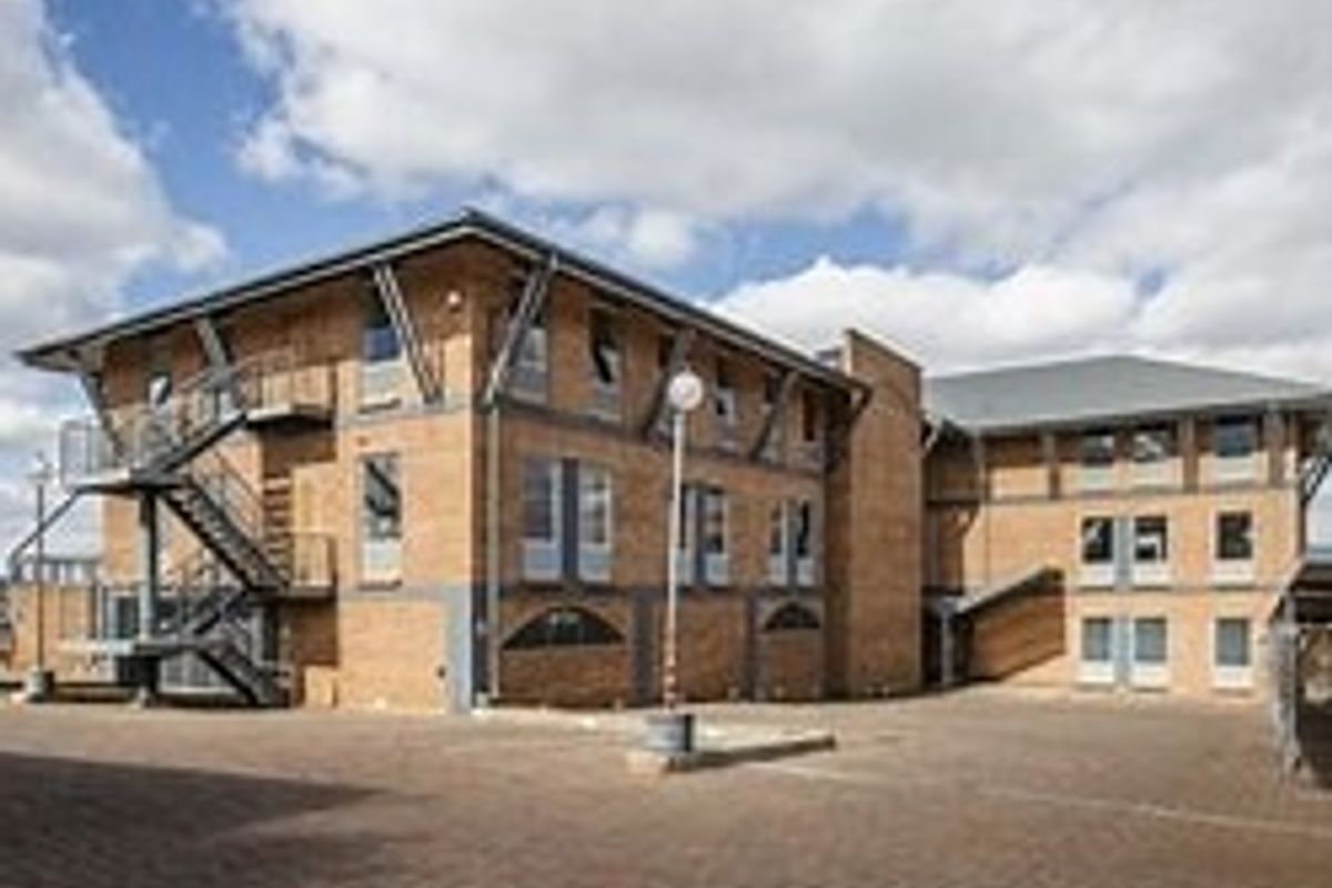 A multi-story commercial brick building featuring an external metal staircase and a paved courtyard area.