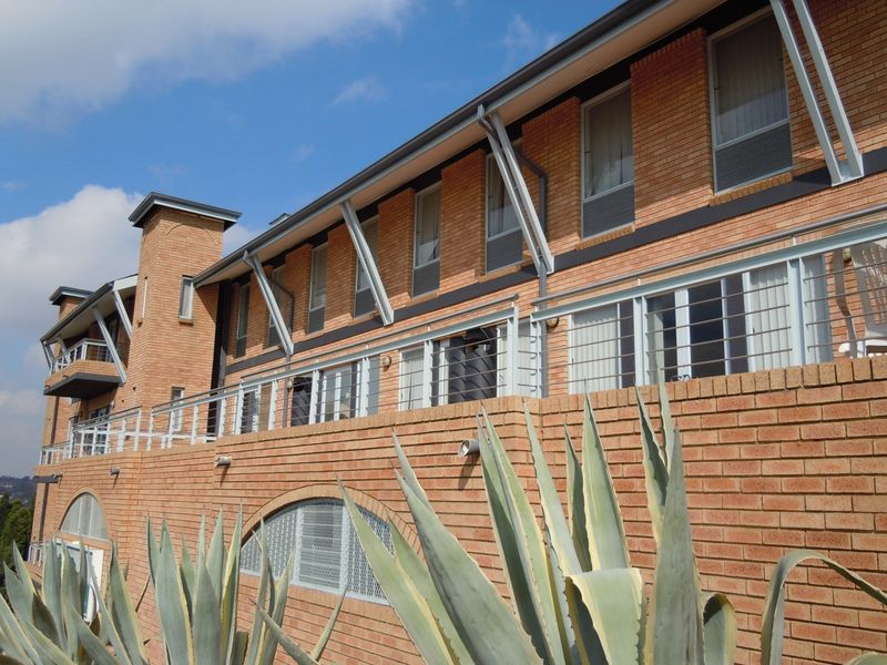 A multi-story commercial building featuring a face brick facade, steel balcony railings, and large sliding glass doors with metal structural supports.