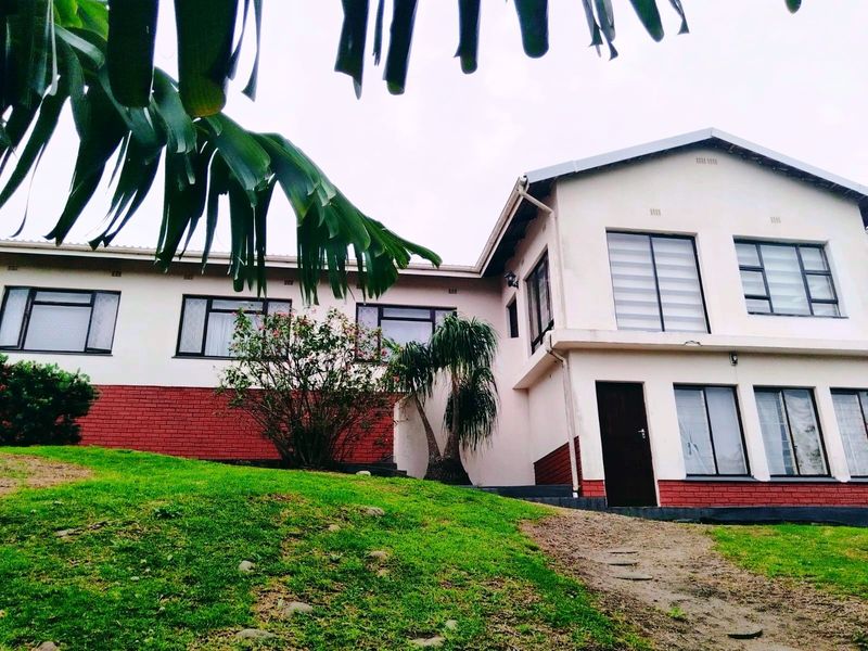 A two-story residential exterior featuring a combination of brick and plastered walls with aluminium window frames and a pitched roof.