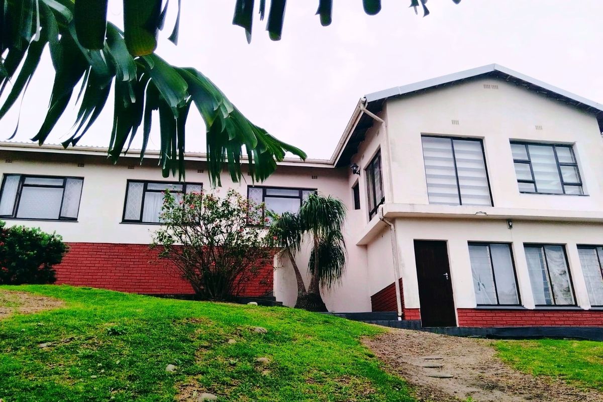 A two-story residential exterior featuring a combination of brick and plastered walls with aluminium window frames and a pitched roof.