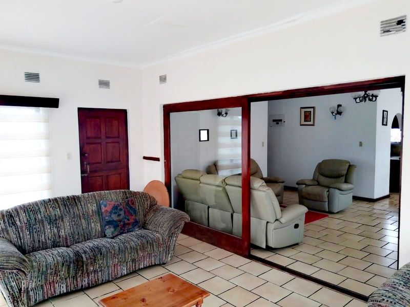 Spacious living area featuring tiled flooring, a large sliding glass door connecting to an adjacent room, and integrated air conditioning vents.