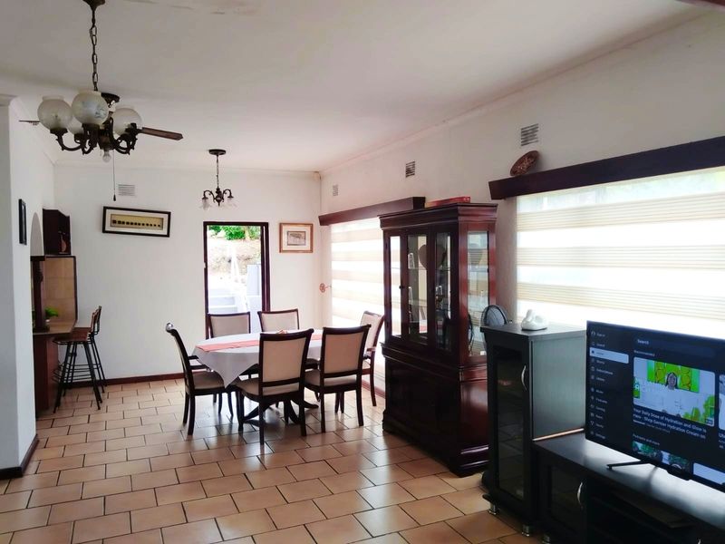 Spacious open-plan living and dining area featuring tiled flooring, ceiling fans, and direct access to the outdoor patio.