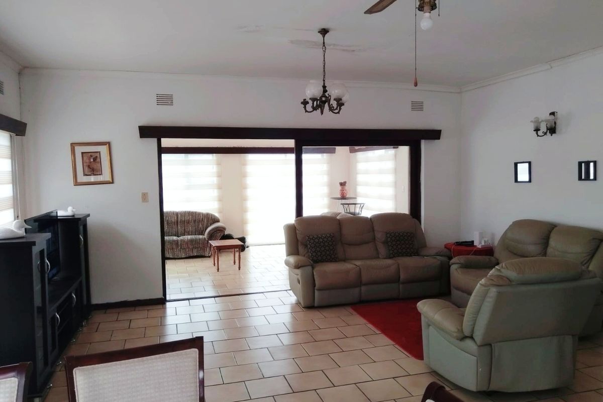 Spacious living area featuring tiled flooring, ceiling fan, and large sliding doors leading to an adjacent sunroom or patio space.