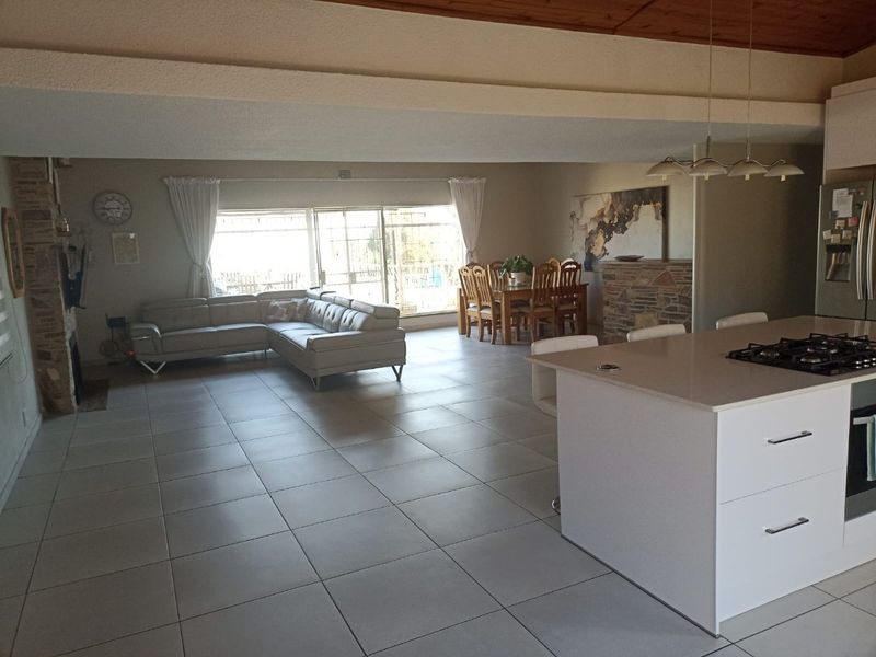 Spacious open-plan living area featuring a modern kitchen island with built-in appliances, stone fireplace, and large sliding doors leading to the outdoor space.
