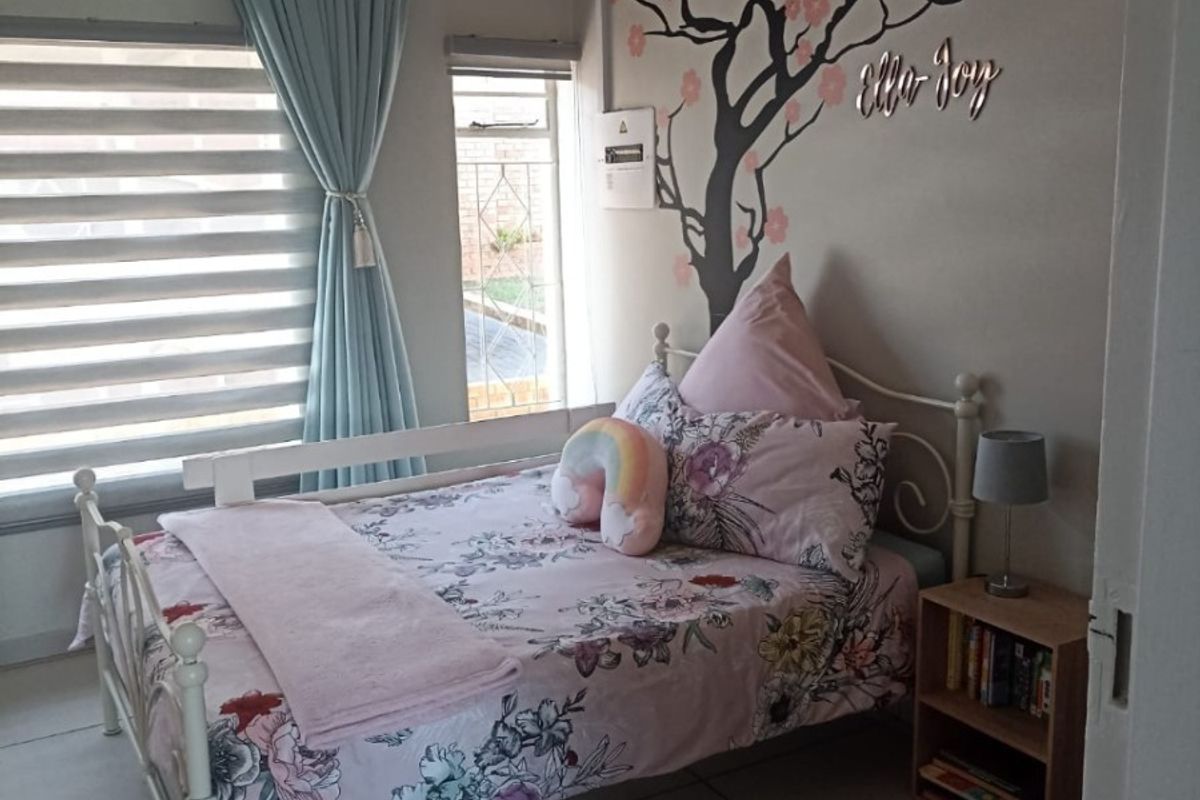A well-maintained bedroom featuring tiled flooring, neutral wall finishes, and natural light through window blinds.