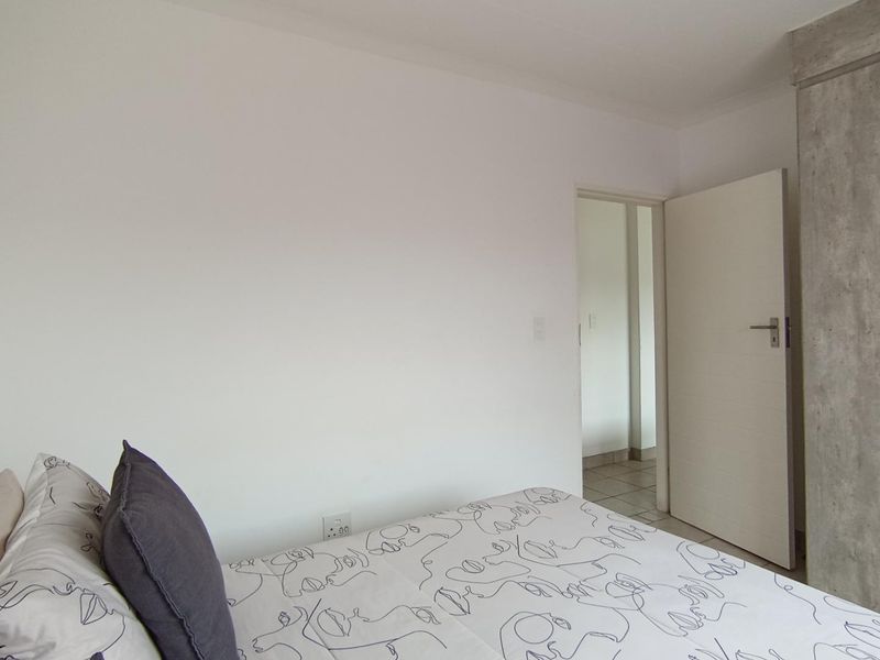A bedroom featuring a built-in wardrobe with a modern concrete-look finish and a standard internal door leading to an adjacent space.