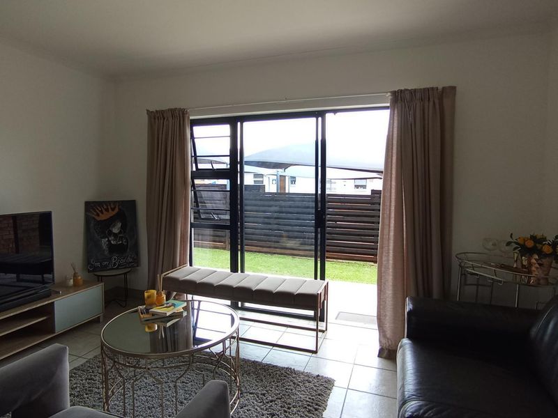 A living room featuring tiled flooring and a large sliding glass door providing direct access to the outdoor area.