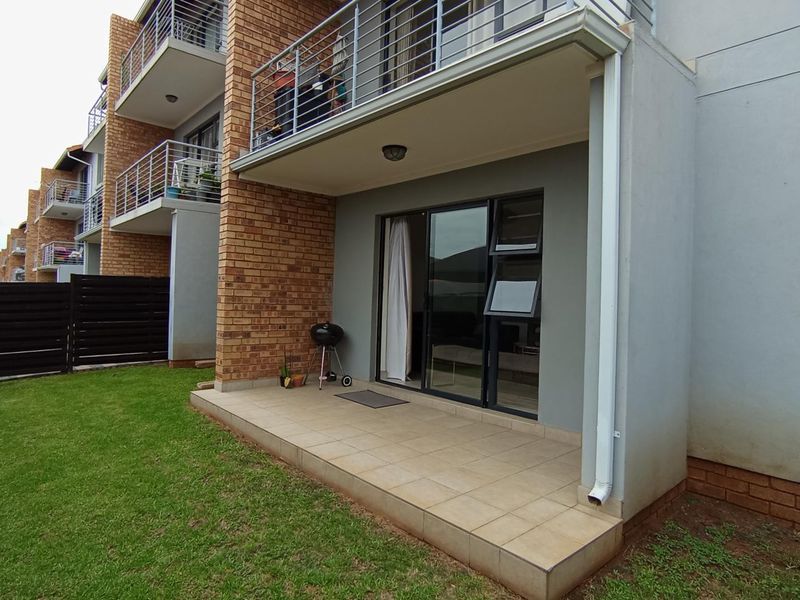 A ground-floor tiled patio area with direct access to the garden through sliding glass doors, featuring brick and rendered wall finishes.
