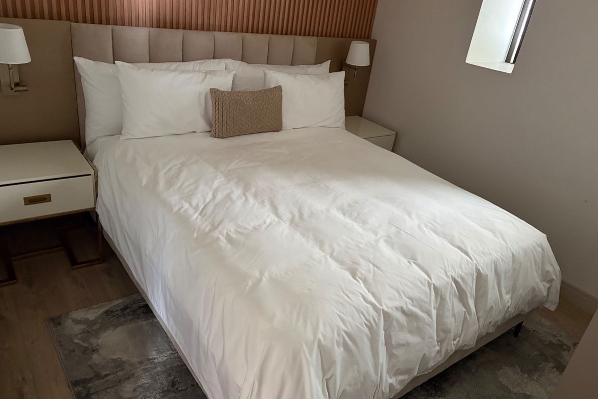 A well-appointed bedroom featuring a modern upholstered headboard, decorative slatted wall paneling, and integrated wall-mounted lighting fixtures.