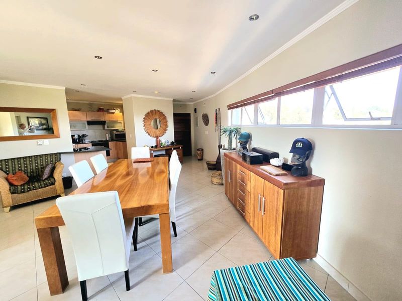 Spacious open-plan living and dining area featuring tiled flooring, recessed lighting, and a functional kitchen with built-in cabinetry and integrated appliances.