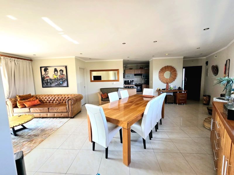 Spacious open-plan living and dining area featuring tiled flooring, recessed lighting, and a functional kitchen with built-in cabinetry and appliances.