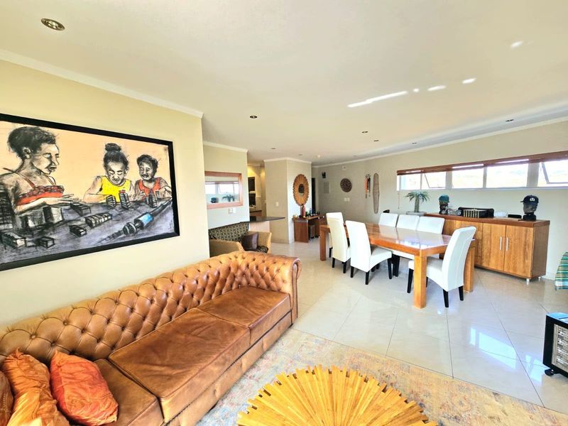 Spacious open-plan living and dining area featuring neutral tiled flooring, recessed downlighting, and integrated cabinetry, creating a bright and functional living space.