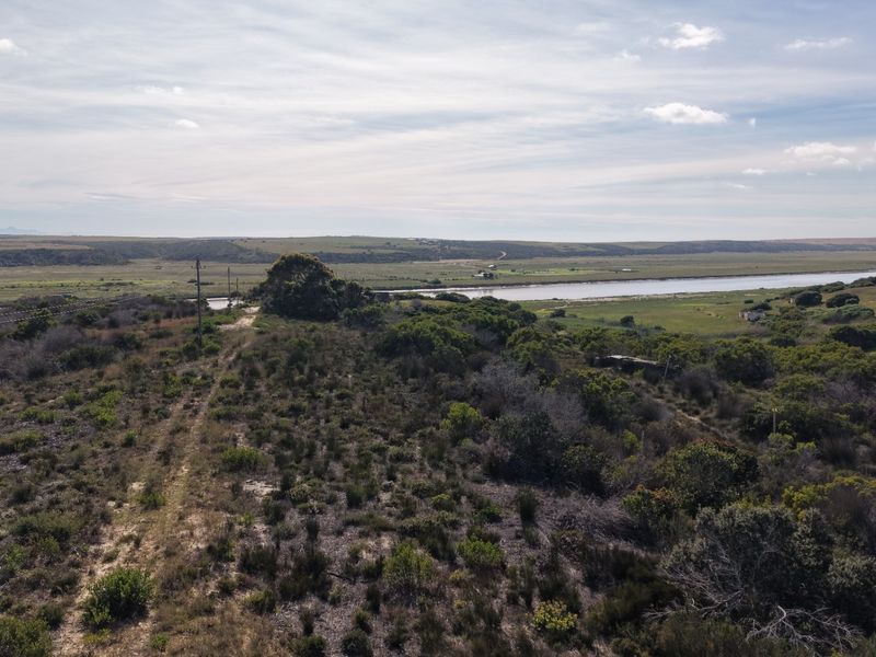An aerial view of the expansive farm landscape featuring natural vegetation and a river running through the property.
