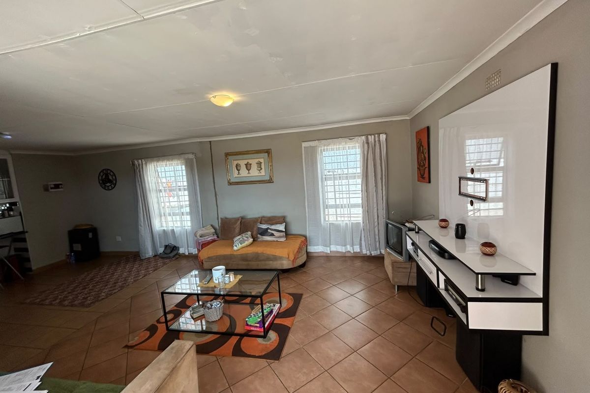 Spacious living room featuring tiled flooring and a built-in media console, offering a functional layout with natural light from multiple windows.