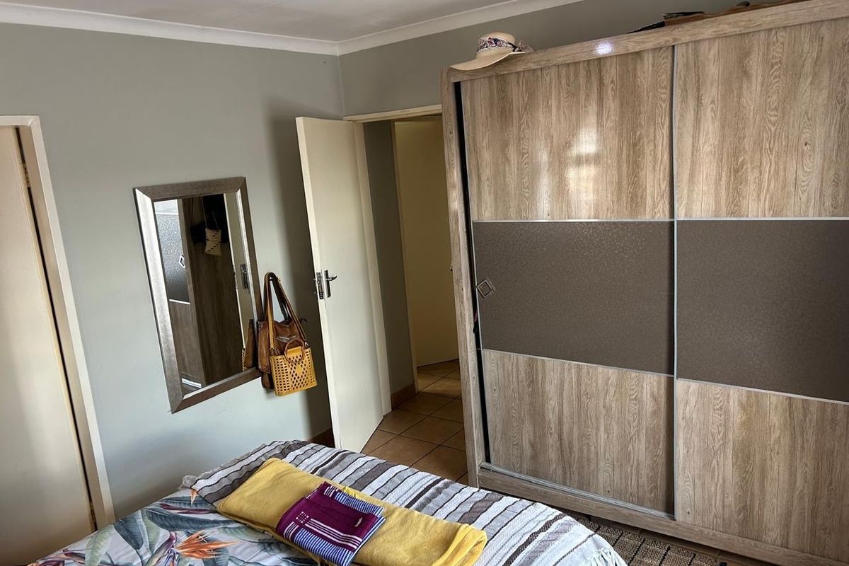 A bedroom featuring a large built-in wardrobe with sliding doors and tiled flooring, providing functional storage space.
