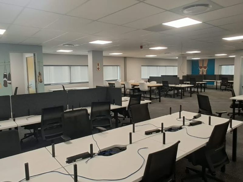 Spacious open-plan office area featuring suspended ceilings, recessed LED lighting, carpeted floors, and modern glass partitions, providing a professional and functional workspace.