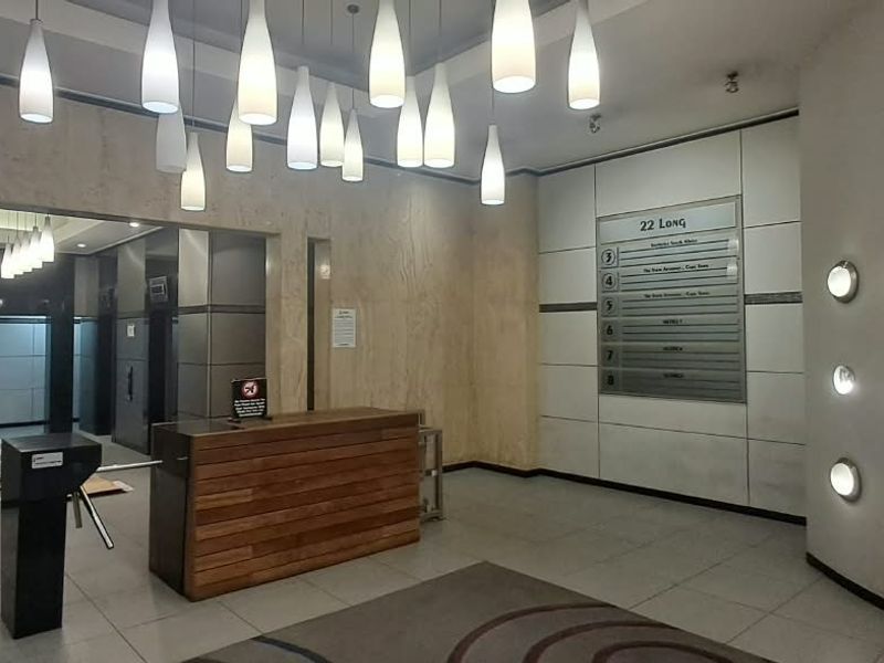 Modern office building lobby featuring a reception desk, security turnstiles, directory board, and elegant marble wall finishes with ambient pendant and recessed lighting.