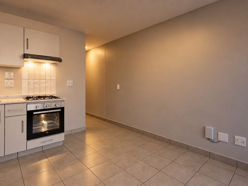 A clean, modern kitchen featuring built-in cabinetry, a gas hob, electric oven, and tiled flooring, offering a functional and well-maintained space.