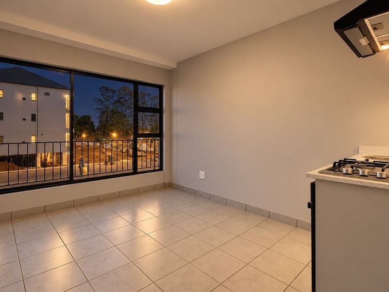 Modern open-plan kitchen and living area featuring tiled floors, a gas hob with extractor, and large windows providing ample natural light.