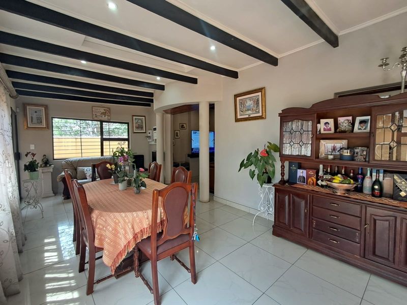 Spacious dining area featuring exposed ceiling beams, tiled flooring, and recessed lighting, creating a warm and inviting atmosphere for family meals.