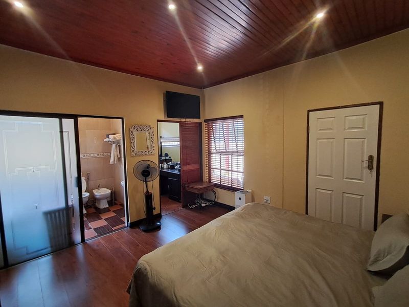 Bedroom featuring timber ceiling, recessed lighting, laminate flooring, and an integrated en-suite bathroom with sliding glass door access.