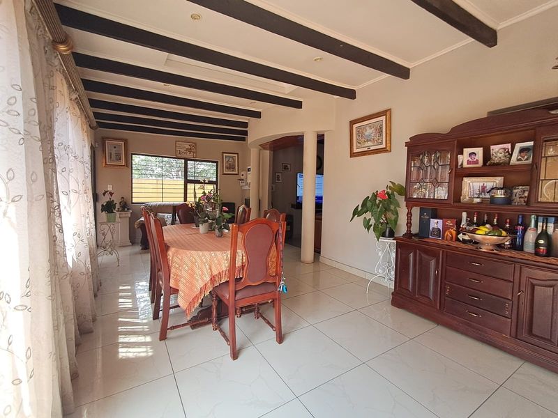 A dining room featuring exposed ceiling beams, tiled flooring, and decorative columns, providing a classic layout for family meals and entertaining.