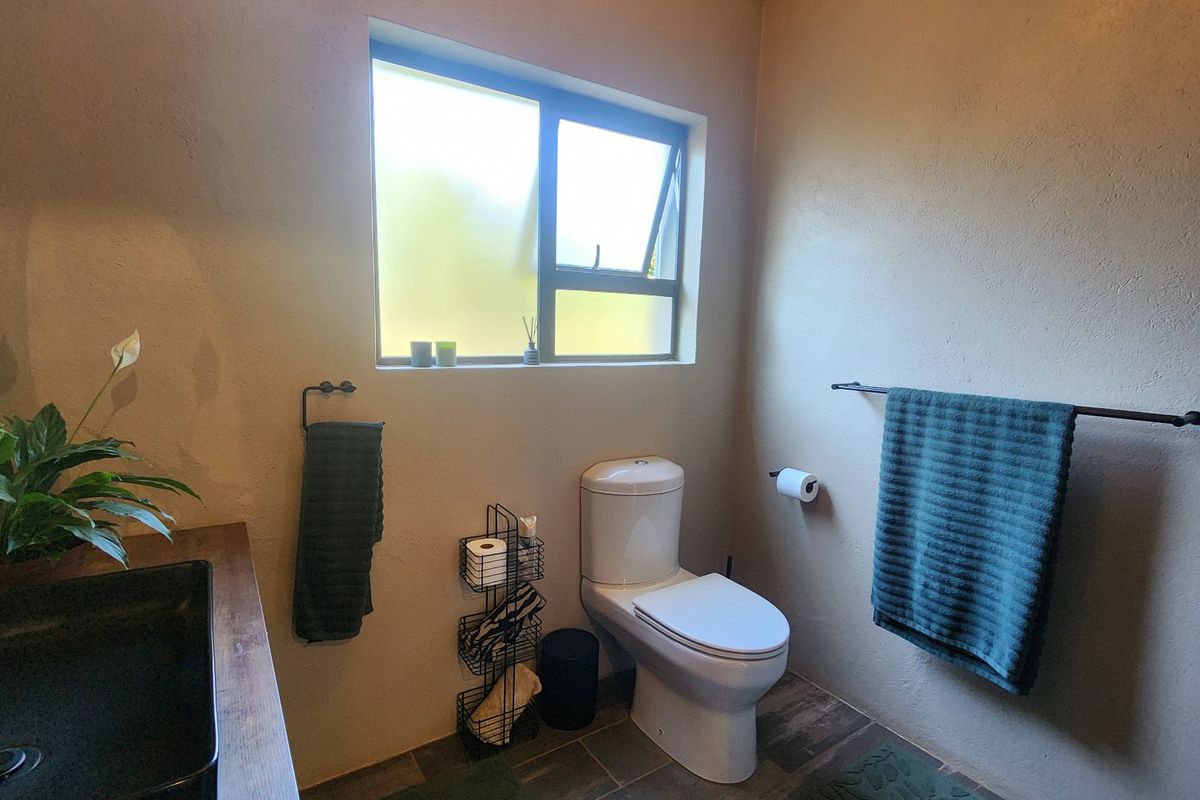 A functional bathroom featuring a modern basin, vanity, and toilet with tiled flooring and natural light from a window.