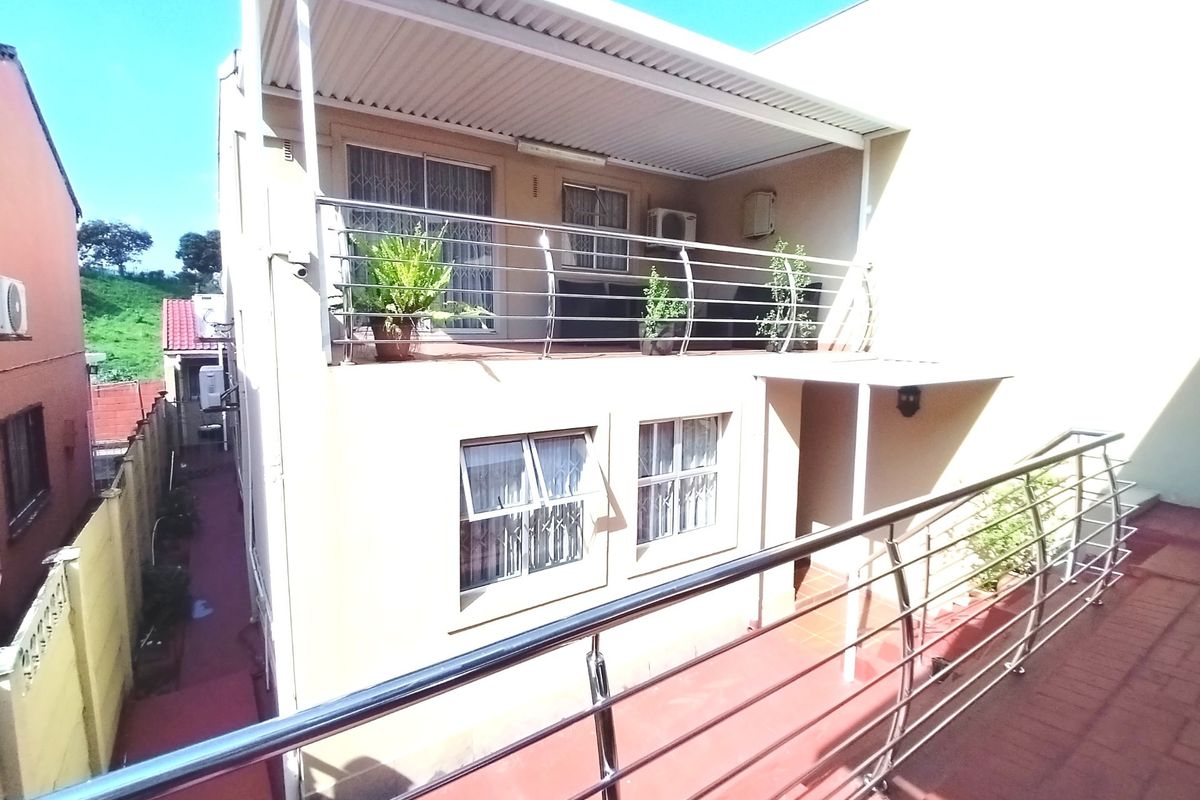 A covered upper-level balcony featuring stainless steel balustrades and tiled flooring, providing an outdoor living space with direct access to the interior.